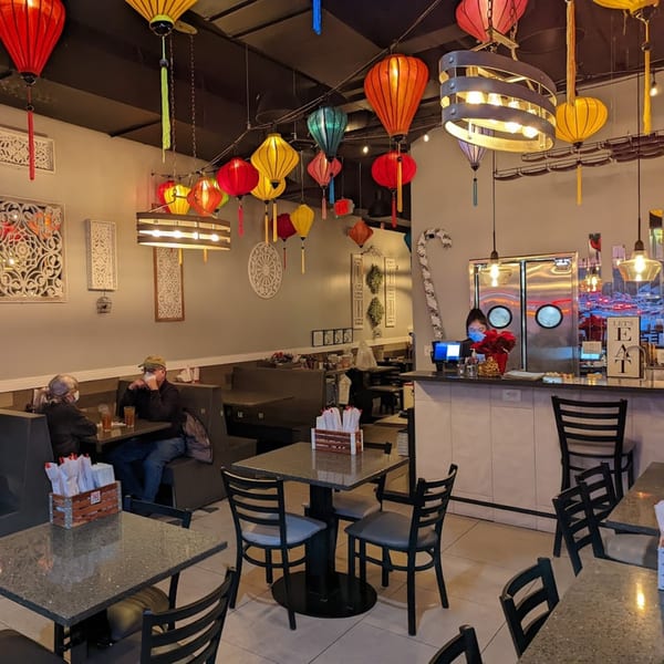 Lantern House Viet Bistro interior with colorful lanterns, diners, and a counter with a masked employee.