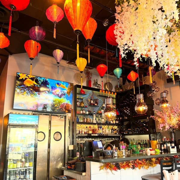 Lantern House Viet Bistro's bar area, adorned with colorful lanterns, a large TV, and a well-stocked bar.